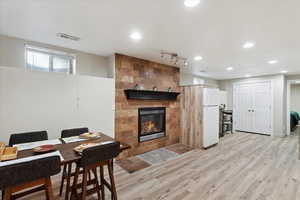Dining space featuring light wood finished floors, a tile fireplace, and recessed lighting