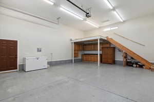 Garage featuring fridge, a garage door opener, and electric panel