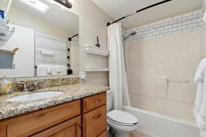 Full bathroom featuring shower / tub combo with curtain, vanity, and toilet