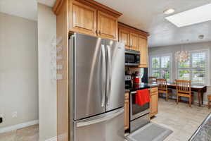 Kitchen with stainless steel appliances, a skylight, a textured ceiling, dark countertops, and a chandelier