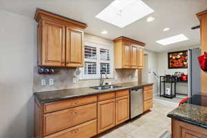 Kitchen featuring stainless steel appliances, a sink, a skylight, tasteful backsplash, and recessed lighting
