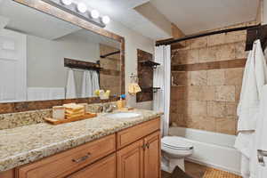 Bathroom featuring vanity, shower / tub combo with curtain, toilet, tile patterned floors, and a textured ceiling