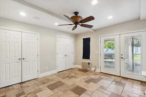 Unfurnished bedroom with french doors, access to exterior, stone tile flooring, multiple closets, and recessed lighting