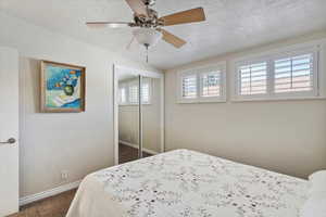 Carpeted bedroom with baseboards, a closet, a textured ceiling, and a ceiling fan