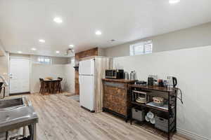 Kitchen featuring freestanding refrigerator, stainless steel microwave, a sink, recessed lighting, and light wood finished floors