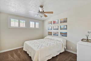 Bedroom with carpet flooring, baseboards, a textured ceiling, and ceiling fan