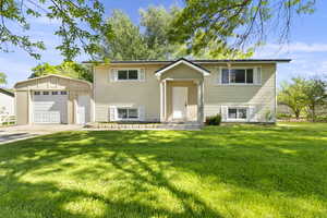 Raised ranch featuring an outdoor structure, a front lawn, driveway, and a garage