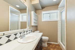 Bathroom featuring toilet, vanity, and a stall shower