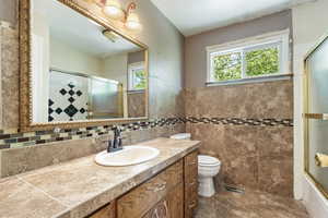 Bathroom with vanity, toilet, and tile walls