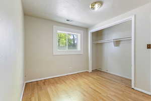 Unfurnished bedroom featuring wood finished floors, a closet, and baseboards