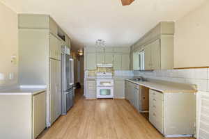 Kitchen with double oven range, freestanding refrigerator, a sink, under cabinet range hood, and light wood finished floors