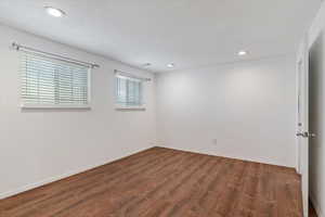Empty room featuring wood finished floors, recessed lighting, baseboards, and a textured ceiling