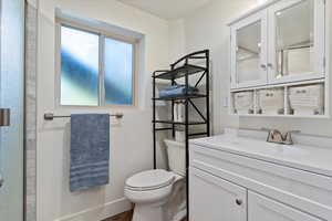 Full bath featuring toilet, vanity, a shower, and baseboards