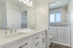 Full bath with a tub to relax in, double vanity, toilet, wood finished floors, and a shower