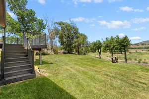 View of green lawn with stairway and a deck