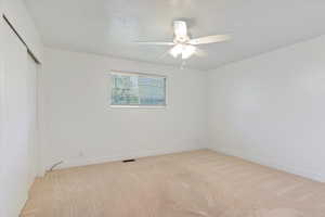 Empty room featuring light carpet, a ceiling fan, and baseboards