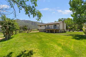 View of green lawn featuring a deck with mountain view