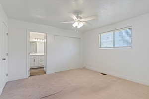 Unfurnished bedroom with light carpet, baseboards, a closet, a sink, and ensuite bath