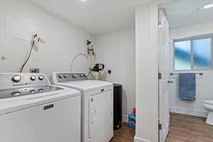 Laundry room featuring washing machine and clothes dryer, wood finished floors, and baseboards
