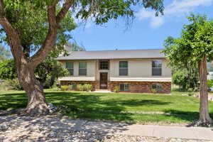 Bi-level home featuring a front yard, a chimney, and brick siding