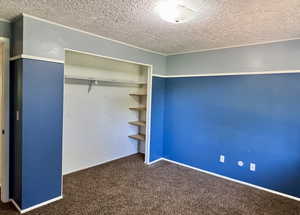 Unfurnished bedroom featuring a textured ceiling, carpet flooring, a closet, and baseboards