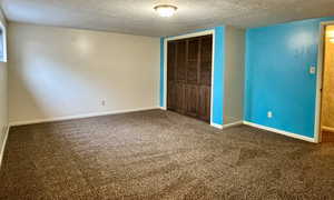 Unfurnished bedroom with a textured ceiling, carpet, a closet, and baseboards
