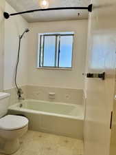Full bath with toilet, tile patterned floors, shower / washtub combination, and a textured ceiling