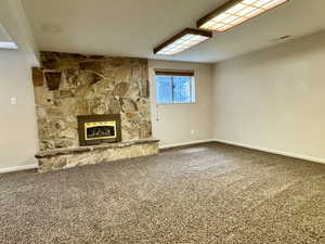 Unfurnished living room featuring carpet floors, baseboards, and a fireplace