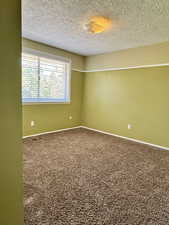 Empty room with carpet flooring and a textured ceiling