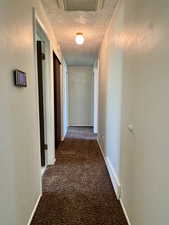Hall with carpet floors, a textured ceiling, and baseboards