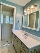 Master Bathroom featuring vanity, a stall shower, and a textured ceiling