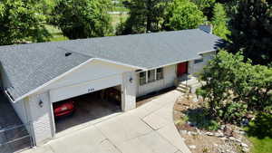 Drone / arial View of front of house with a shingled roof, concrete driveway, an attached garage, and a chimney