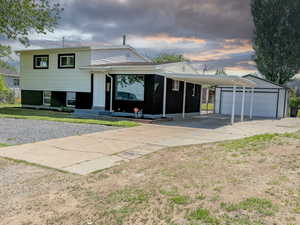 Property at dusk featuring driveway and a detached garage