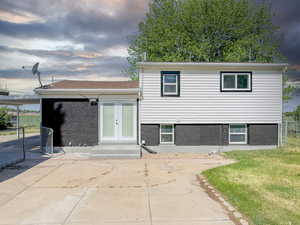Split level home featuring french doors, brick siding, and a patio