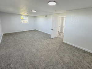 Spare room featuring carpet flooring, baseboards, and a textured ceiling