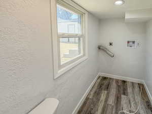 Laundry area with hookup for an electric dryer, baseboards, dark wood-style flooring, hookup for a washing machine, and a textured ceiling