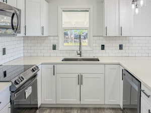 Kitchen with stainless steel appliances, a sink, backsplash, and light countertops