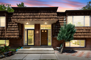 View of exterior entry with brick siding and mansard roof