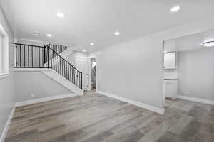 Unfurnished living room with stairs, light wood-type flooring, recessed lighting, and baseboards