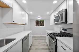 Kitchen featuring appliances with stainless steel finishes, light countertops, recessed lighting, light wood finished floors, and baseboards