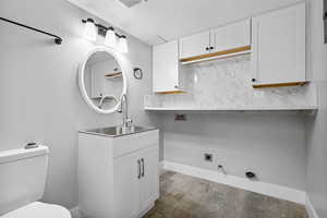 Bathroom featuring vanity, backsplash, wood finished floors, toilet, and baseboards