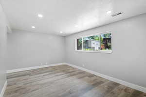 Spare room featuring baseboards, recessed lighting, wood finished floors, and a textured ceiling