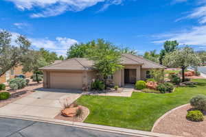 Single story home with stucco siding, a garage, driveway, stone siding, and a front yard