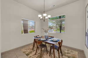 Dining room with a chandelier, light tile patterned flooring, and baseboards