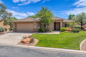 View of front facade with stone siding, an attached garage, concrete driveway, stucco siding, and a front lawn