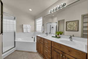 Bathroom with a shower stall, double vanity, a bath, and tile patterned flooring