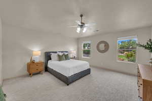 Bedroom featuring baseboards, light colored carpet, and ceiling fan
