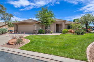 View of front of house featuring stucco siding, driveway, a garage, and a front lawn