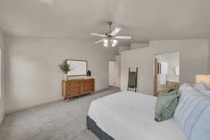 Bedroom with vaulted ceiling, light colored carpet, baseboards, connected bathroom, and ceiling fan