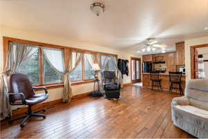 Living room featuring baseboards, hardwood / wood-style flooring, and a ceiling fan